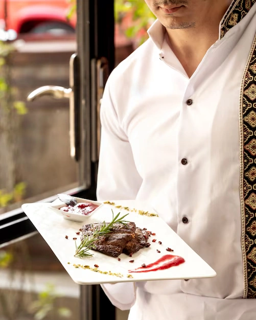 chef-holding-plate-with-cooked-meat-and-sauces